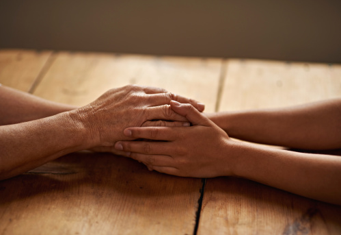 A cropped shot of a woman holding a loved one's hand in support