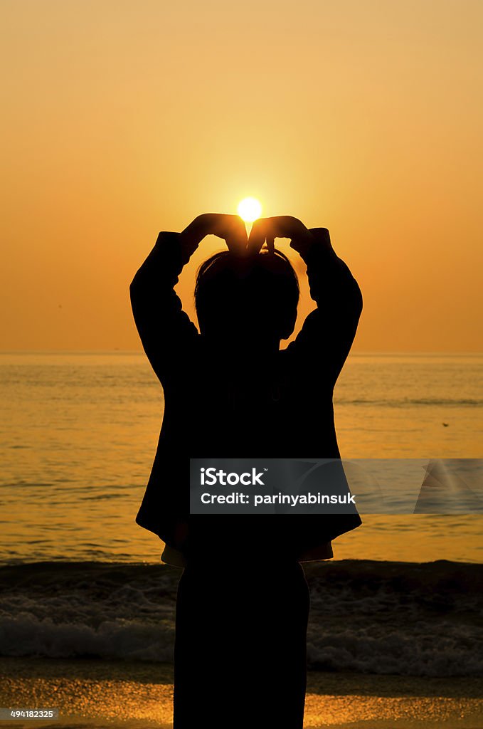 Silhouette Boy hand making a heart shape Silhouette Boy hand making a heart shape with sunrise on beach Back Lit Stock Photo
