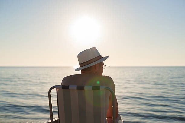 istock man sitting sunset beach backlight lens flare 494184492