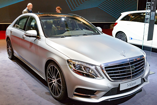 Amsterdam, The Netherlands - April 16, 2015: Mercedes-Benz S-Class S 500 e PLUG-IN HYBRID on display during the 2015 Amsterdam motor show. The S 500 e is a plug-in hybrid version of the long wheelbase S-Class sedan with a 3.0-litre V6 twin turbo engine and electric motor with an externally rechargeable battery. There are people looking around and other cars on display in the background. 