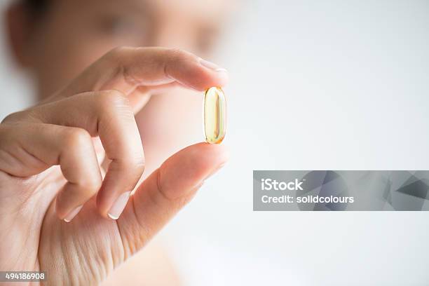 Woman Holding And Showing Omega 3 Capsule Stock Photo - Download Image Now - Capsule - Medicine, Nutritional Supplement, Holding