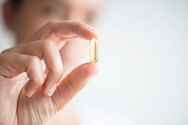 mulher segurando e mostrando omega 3 cápsula - óleo de fígado de bacalhau - fotografias e filmes do acervo