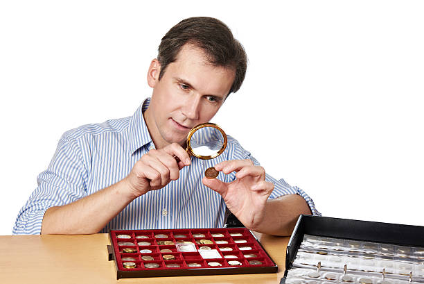 istock Man numismatist examines  coin with magnifying glass 494190608