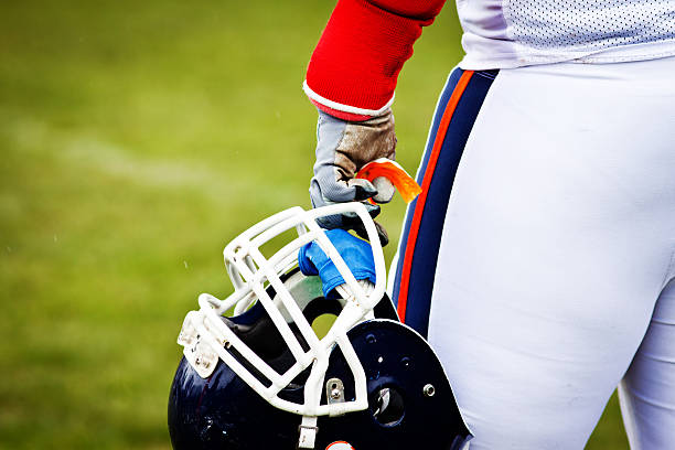 Elementary age Caucasian little boy is scowling intimidatingly while wearing a football uniform and helmet during a little league football game.