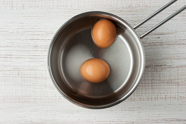 Eggs in water in a metal pan top view stock photo