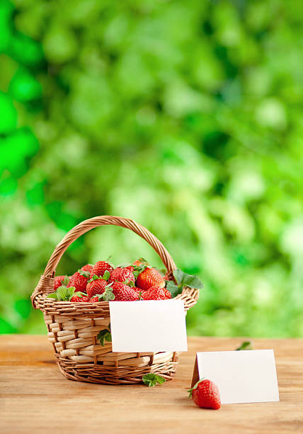 fresh strawberries in a basket on isolated white background. Straw hat with leaves and flower heads.