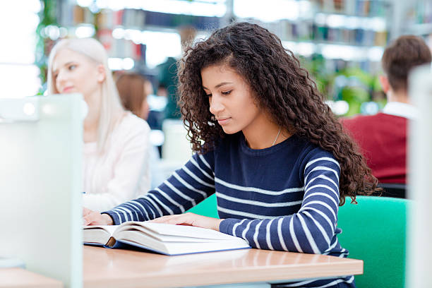 istock Afro american woman reading book in classroom 494197020