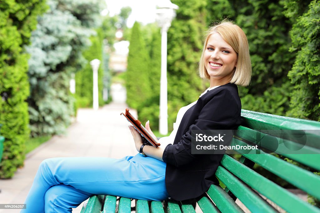 Happy woman sitting on the bench Happy woman sitting on the bench with tablet computer Adult Stock Photo