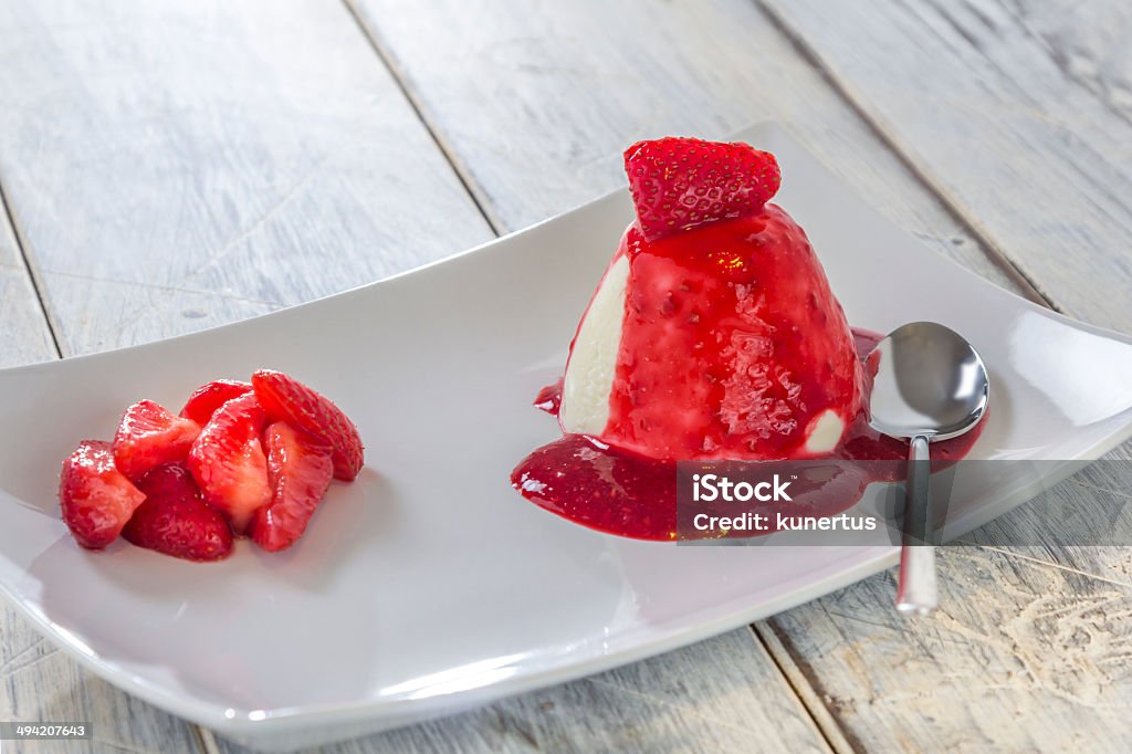 Panna cotta with Strawberry Panna cotta with strawberries and red sauce on a white plate on a wooden table Strawberry Stock Photo