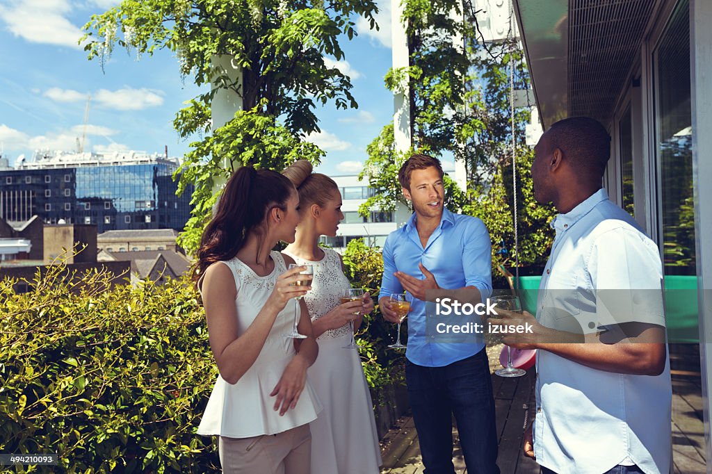 Outdoor party Group of friends enjoying their wine on the terrace with cityscape in the background.  Balcony Stock Photo