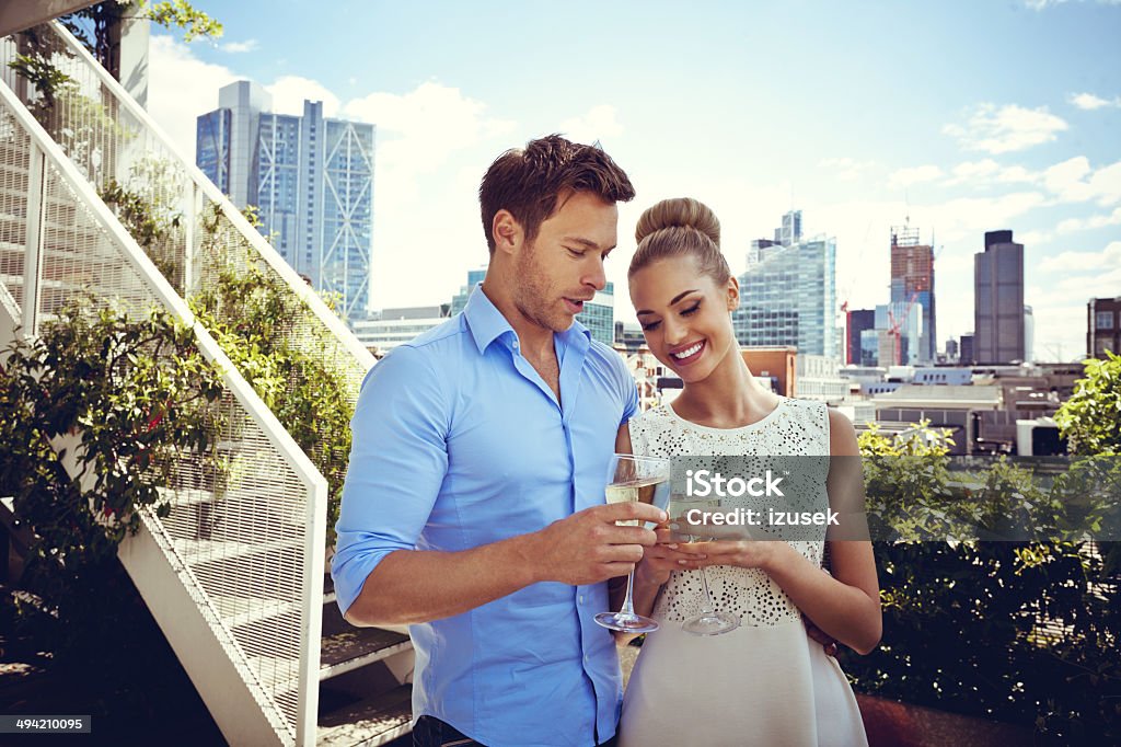 Romantic couple Outdoor portrait of affectionate couple standing with wine glasses on the terrace with cityscape in the background. Luxury Stock Photo