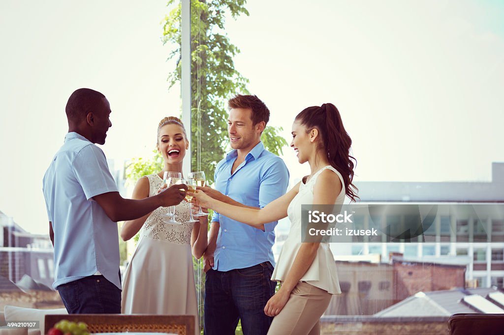 Party Group of friends enjoying their party in the livingroom with cityscape in the background.  Luxury Stock Photo