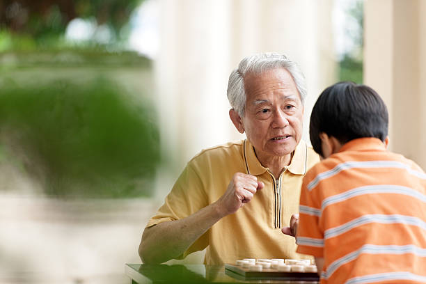 abuelo y nieto jugando xiangqi (ajedrez chino) - chinese chess fotografías e imágenes de stock