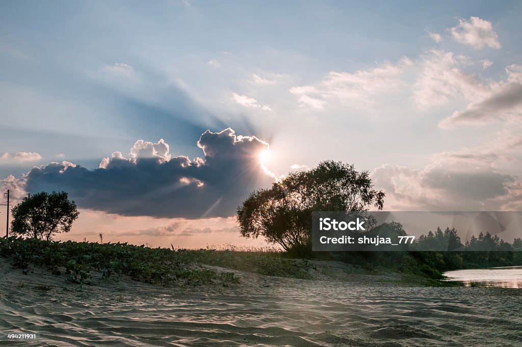 Spiaggia di sabbia e bush contro sunbeams dietro cloud sfondo - Foto stock royalty-free di Acqua