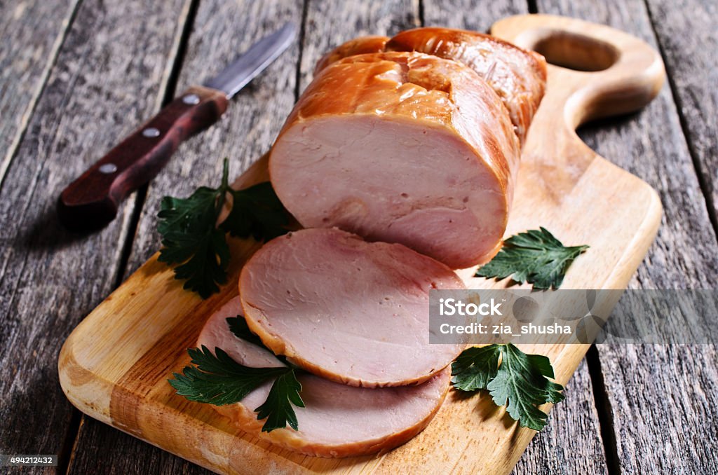Piece of cooked ham Piece of cooked ham on a wooden surface. Selective focus. 2015 Stock Photo