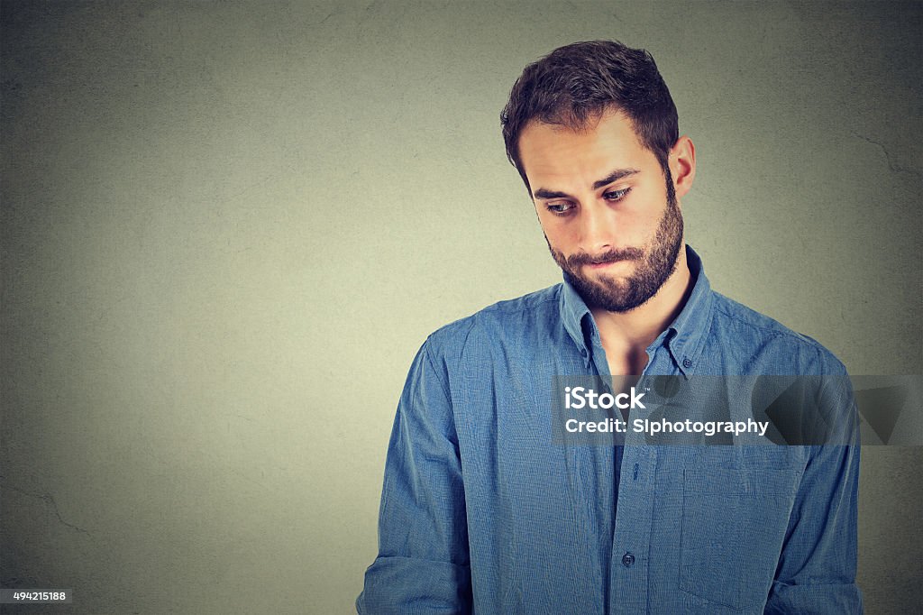 Shy young handsome man feels awkward Lack of confidence. Shy young handsome man feels awkward isolated on grey wall background. Human emotion body language life perception Shy Stock Photo