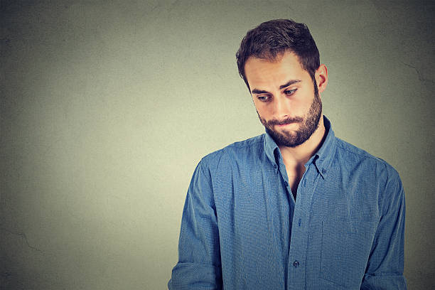 Shy young handsome man feels awkward Lack of confidence. Shy young handsome man feels awkward isolated on grey wall background. Human emotion body language life perception man regret stock pictures, royalty-free photos & images