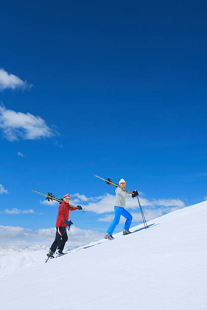 neve esquiadores casal maduro feliz mulheres e homens que transportem esquis - pair couple mid adult happiness imagens e fotografias de stock