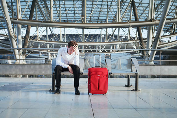 delay of the flight problem in the airport, tired man waiting in the terminal with luggage delayed sign photos stock pictures, royalty-free photos & images