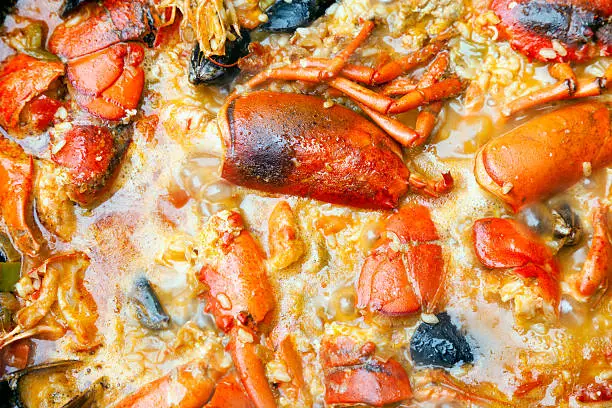 Arroz caldoso de bogavante; paella with homard and lobester close-up.