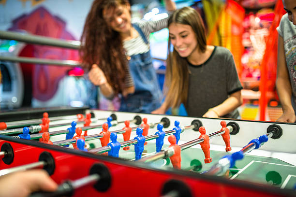 znajomych, grając w gry gra w piłkarzyki - amusement arcade zdjęcia i obrazy z banku zdjęć