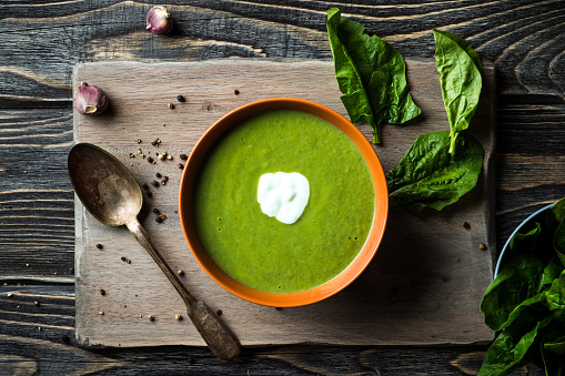 Homemade spinach soup in a bowl on wooden background