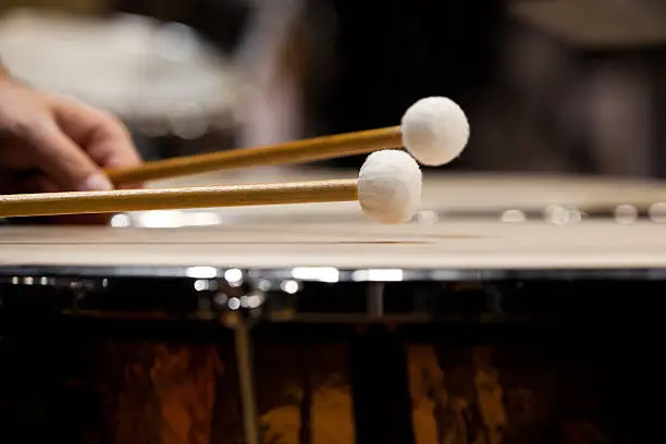 Drum sticks hitting the timpani closeup