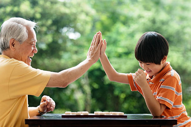 Grandfather and grandson playing Xiangqi (chinese chess) Grandfather and grandson playing Xiangqi (chinese chess) china chinese ethnicity smiling grandparent stock pictures, royalty-free photos & images