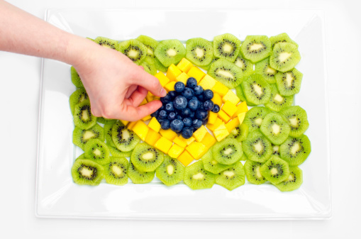 A hand is decorating fresh fruit for a party. 