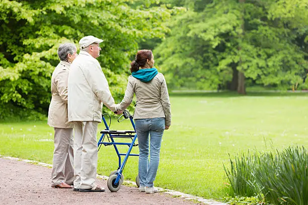 Senior couple outdoors in the park with caregiver