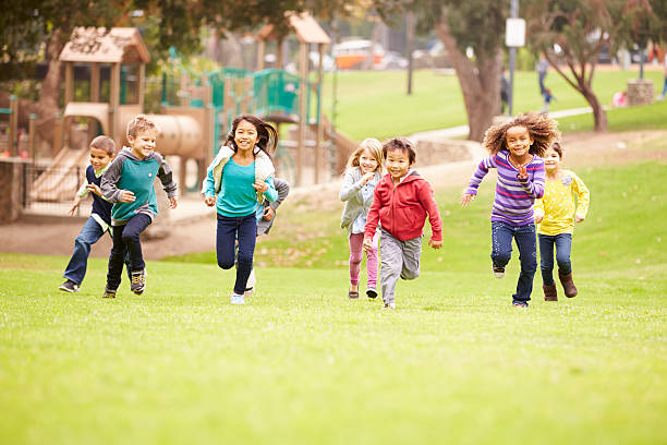 grupo de niños corriendo hacia la cámara en el parque - parque infantil fotografías e imágenes de stock