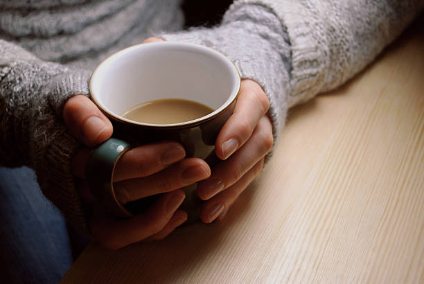 istock Woman holds hot drink at a table under lamplight 494243778