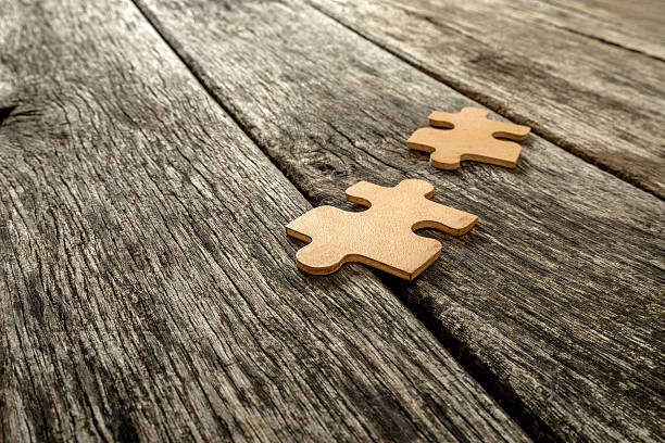 istock Two puzzle pieces lying on wooden rustic boards 494256328