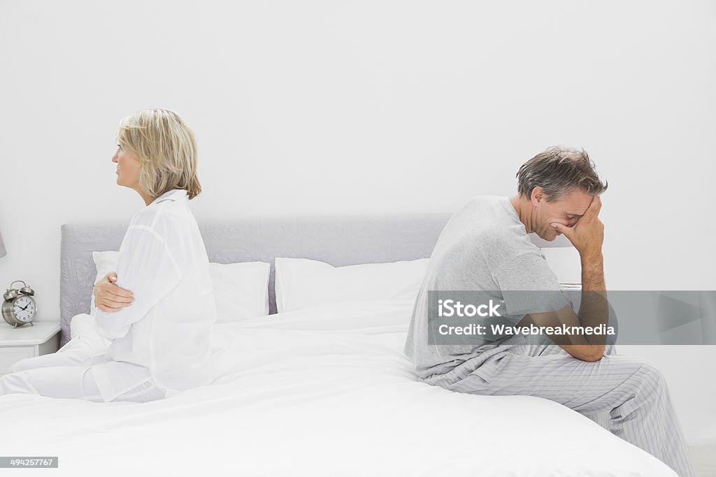 Couple sitting on opposite sides of bed Couple sitting on opposite sides of bed after a dispute Sadness Stock Photo