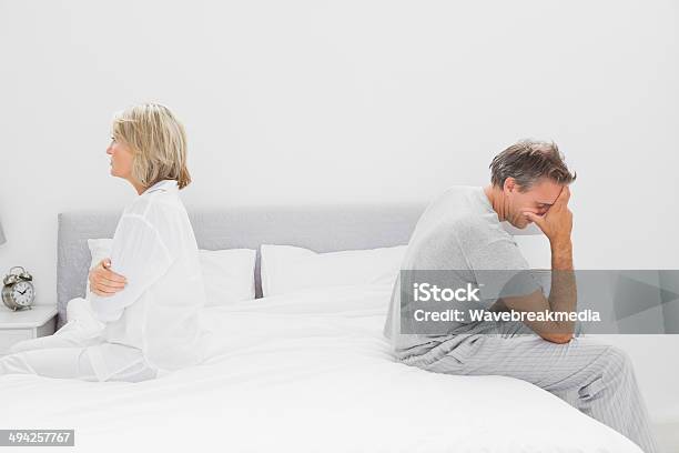 Couple Sitting On Opposite Sides Of Bed Stock Photo - Download Image Now - Sadness, Bed - Furniture, Mature Couple