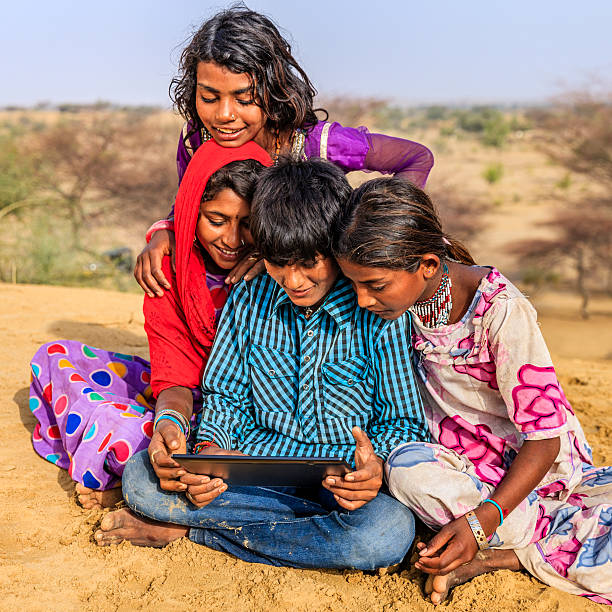 istock Happy Indian children using digital tablet, desert village, India 494258458