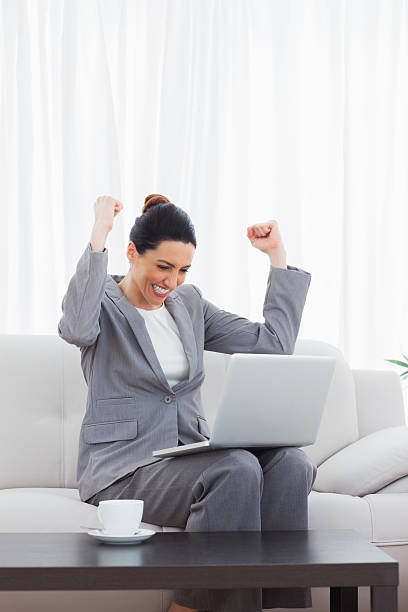 istock Busineswoman sitting on sofa using laptop cheering 494261869