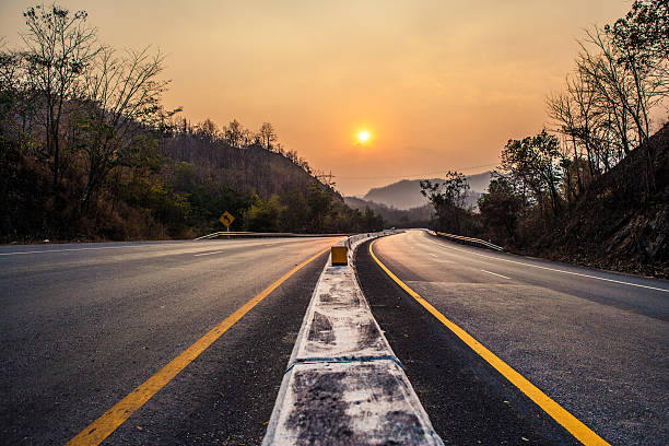 route au coucher du soleil - asphalt two lane highway natural phenomenon fog photos et images de collection