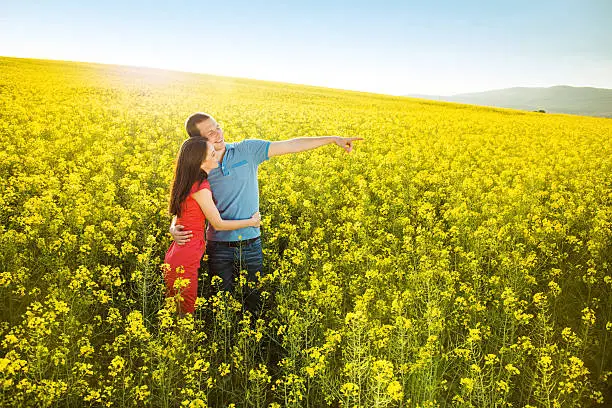 Happy young couple in love hugging in yellow colza field