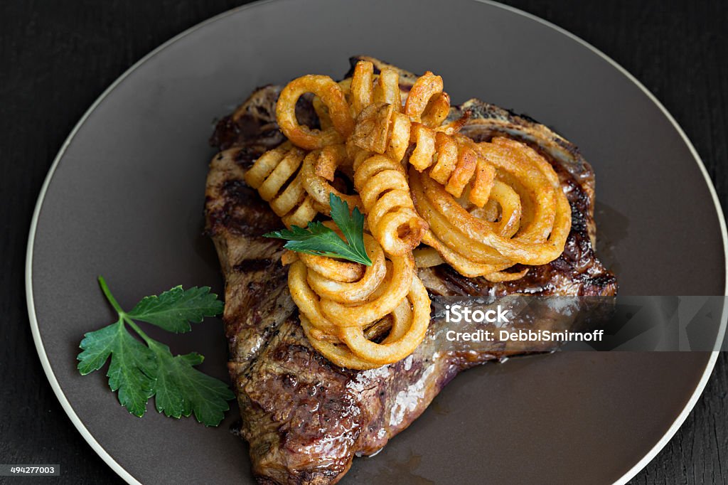 Bistecca e patatine fritte a ricciolo - Foto stock royalty-free di Alla brace