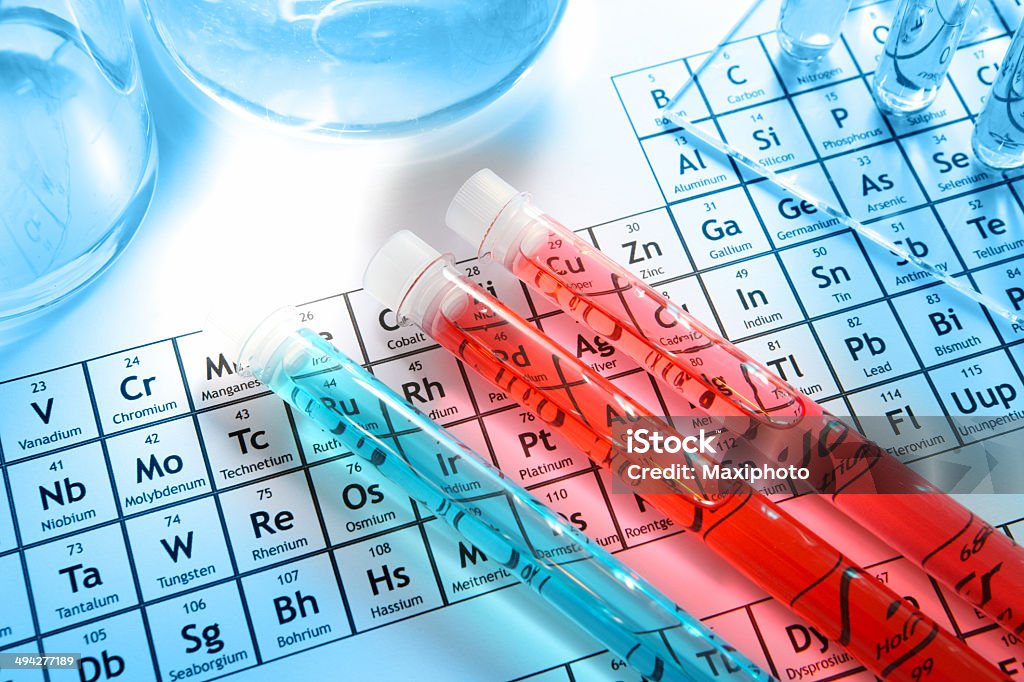 Chemistry research laboratory, glass equipment, test tubes, element periodic table Chemistry research laboratory with glass equipment, test tubes with red liquid on periodic table background showing chemical elements. Selective focus. Light blue background. Periodic Table Stock Photo