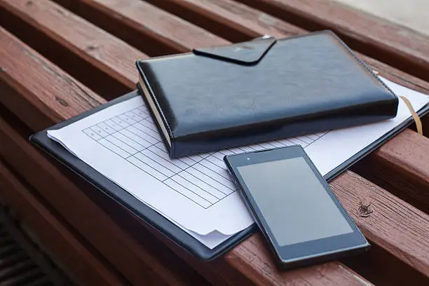 Notes and mobile phone on woodenbench.