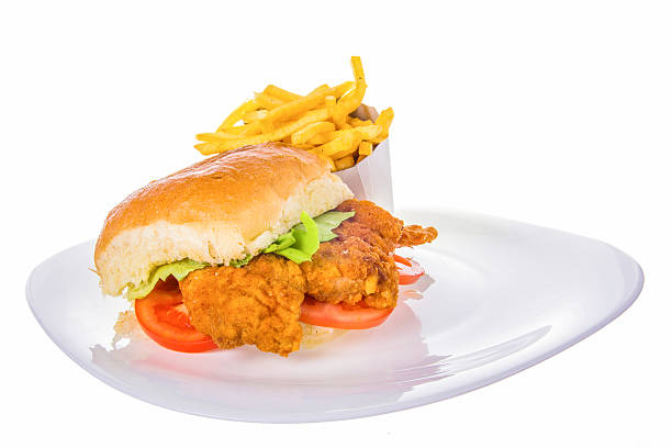 fried chicken in bread bun with french fries on plate stock photo
