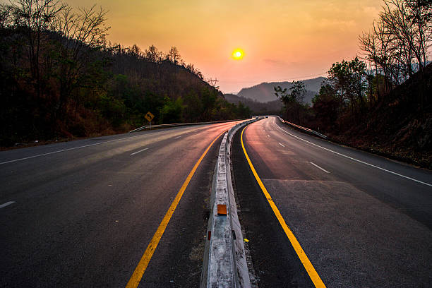 route au coucher du soleil - asphalt two lane highway natural phenomenon fog photos et images de collection