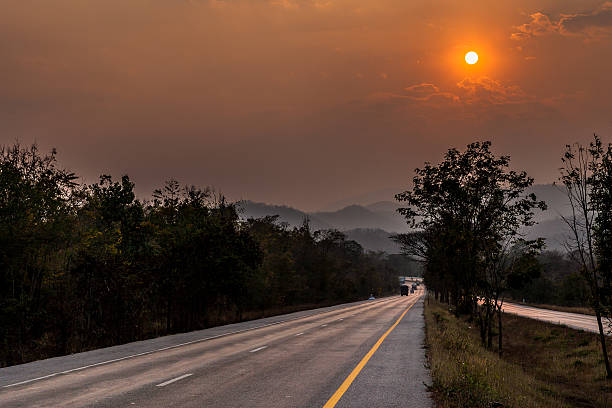 route au coucher du soleil - asphalt two lane highway natural phenomenon fog photos et images de collection