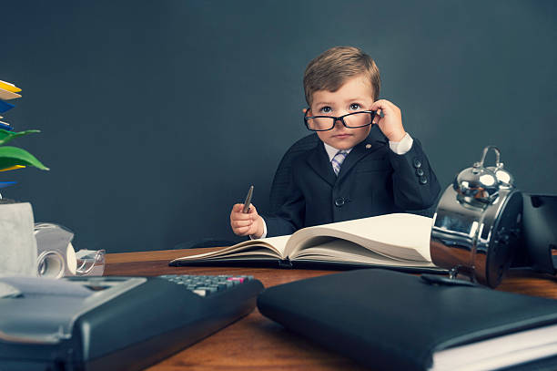 istock Young boy dressed in suit working at desk. 494278882