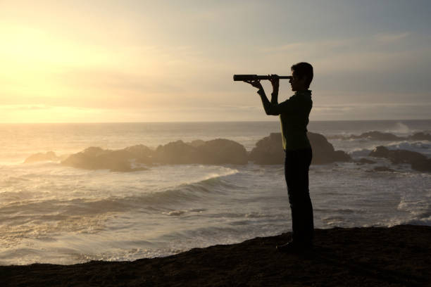 istock Woman with spyglass looking toward ocean 494279534