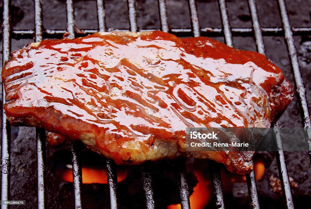 Steak Cooking On The Barbecue Thick juicy Sirloin Steak slathered with barbecue sauce cooking on the grill Barbecue - Meal Stock Photo