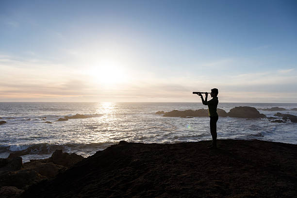 istock Woman with spyglass looking toward ocean 494281590