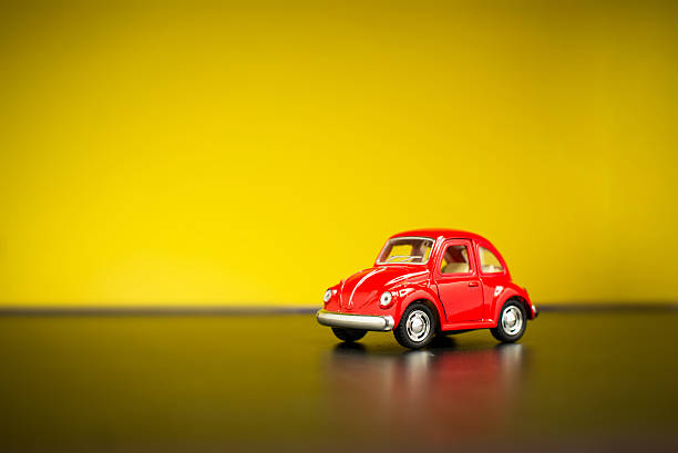 Miniature toy cars on green grass over blue sky and clouds.